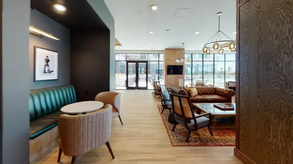 Teal channel-tufted banquette with cafe tables and upholstered chairs in an apartment amenity lounge, Minnesota