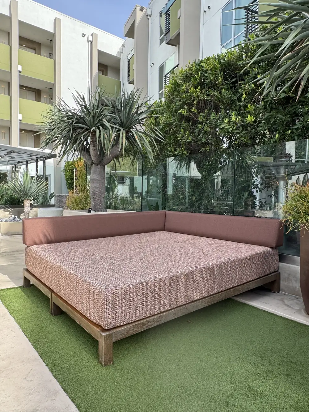 Upholstered cabana daybed with a wood base on artificial turf at The Brio, Glendale