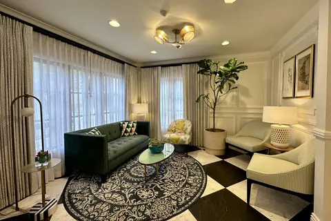 Lobby sitting room at the Candy Cane Inn, Anaheim: a dark green sofa and upholstered armchairs on a black and white floor