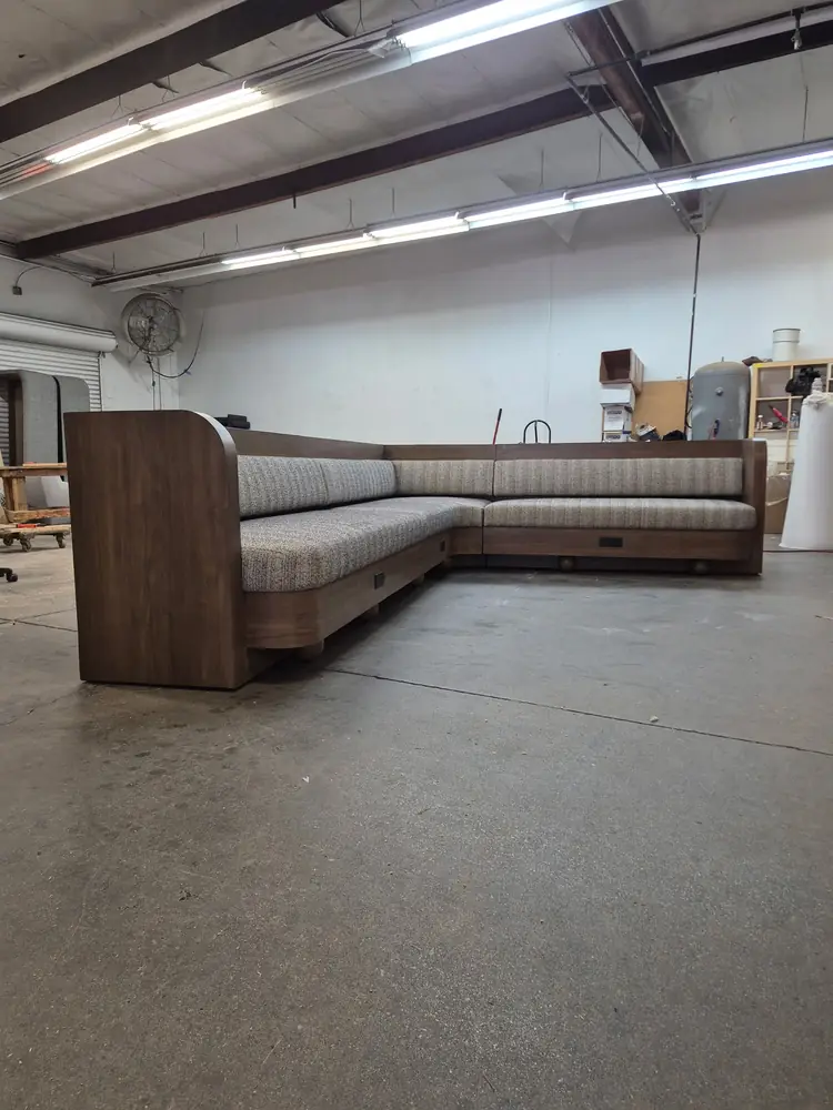 An L-shaped banquette with wood side panels standing on the Trend factory floor before delivery